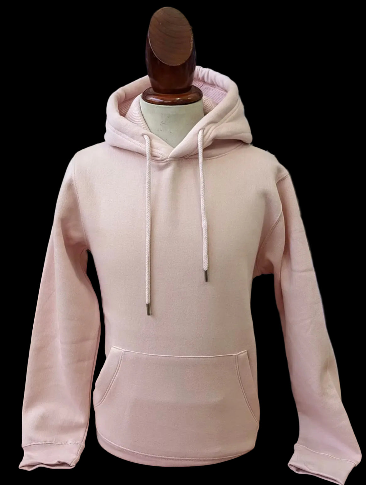 Pink hoodie on a mannequin with a blurred background of folded clothes.