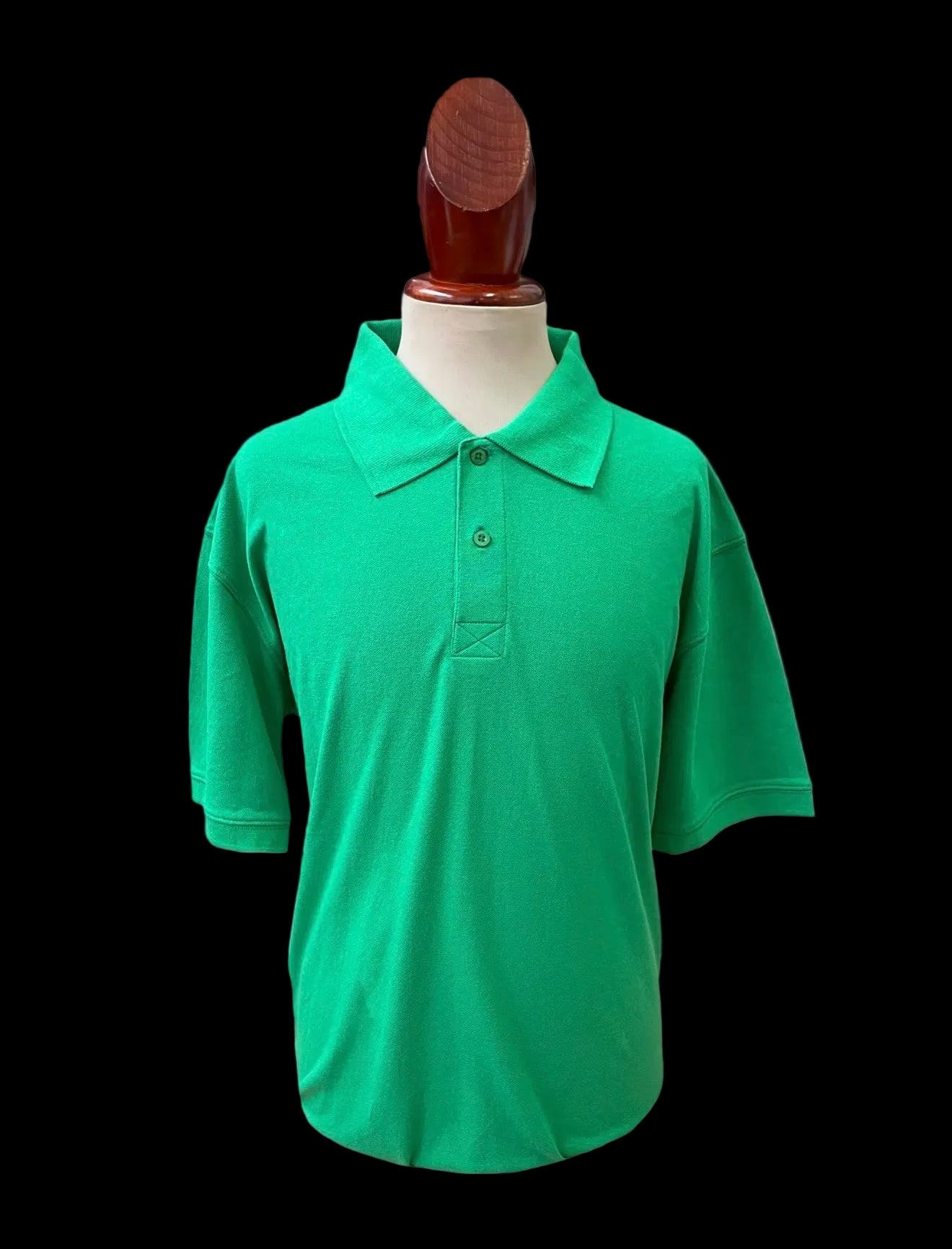 Green polo shirt blank on a mannequin against a plain background
