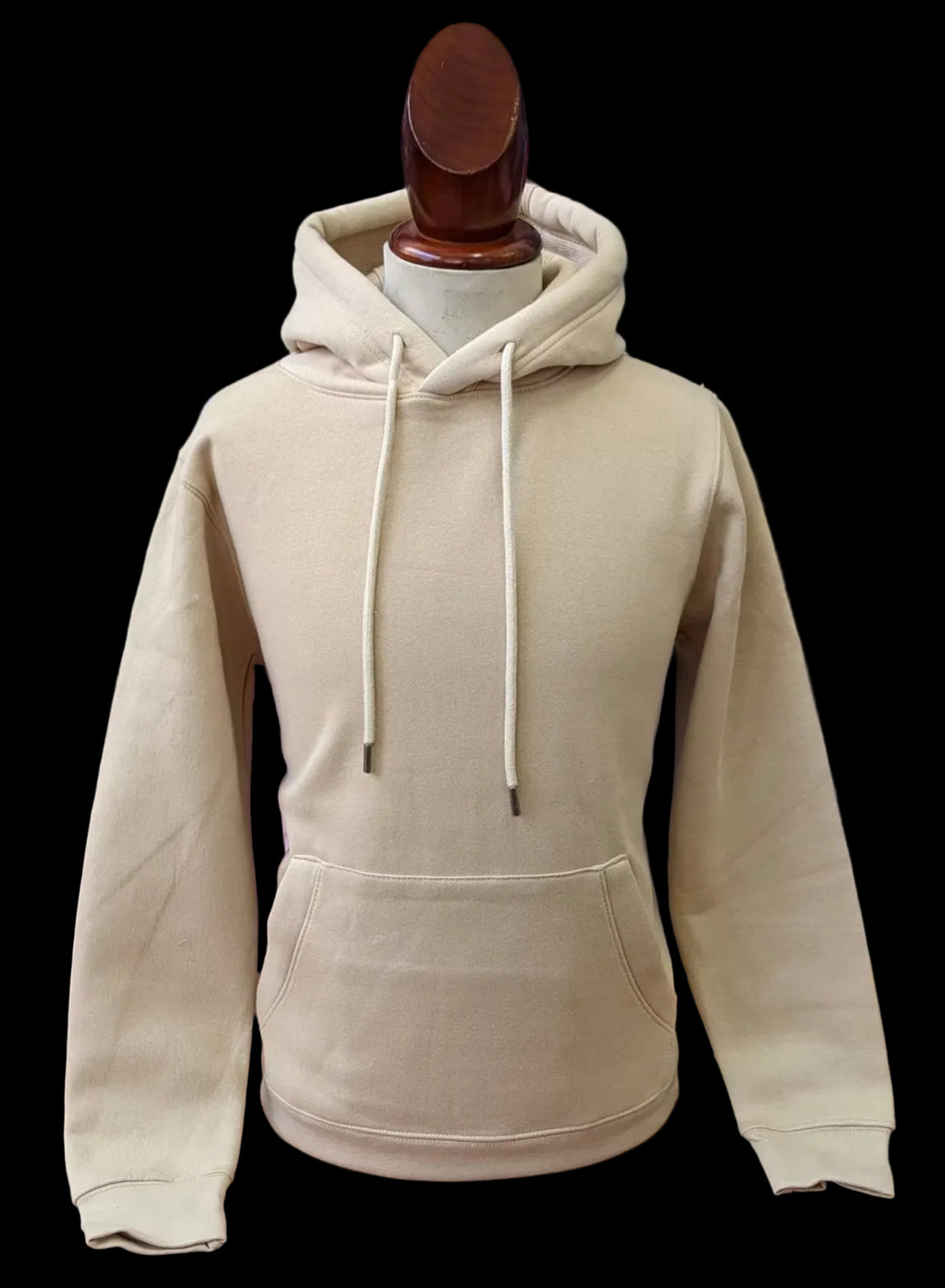 Beige hoodie on a mannequin against a background of folded clothes.